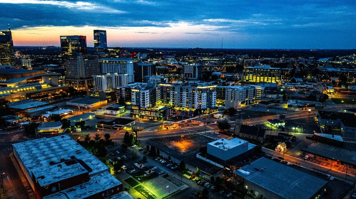 A panoramic city skyline at sunset, with illuminated buildings and busy streets below. The view captures Nashville's energetic vibe and provides the perfect backdrop for toasting milestones and exploring the city together.